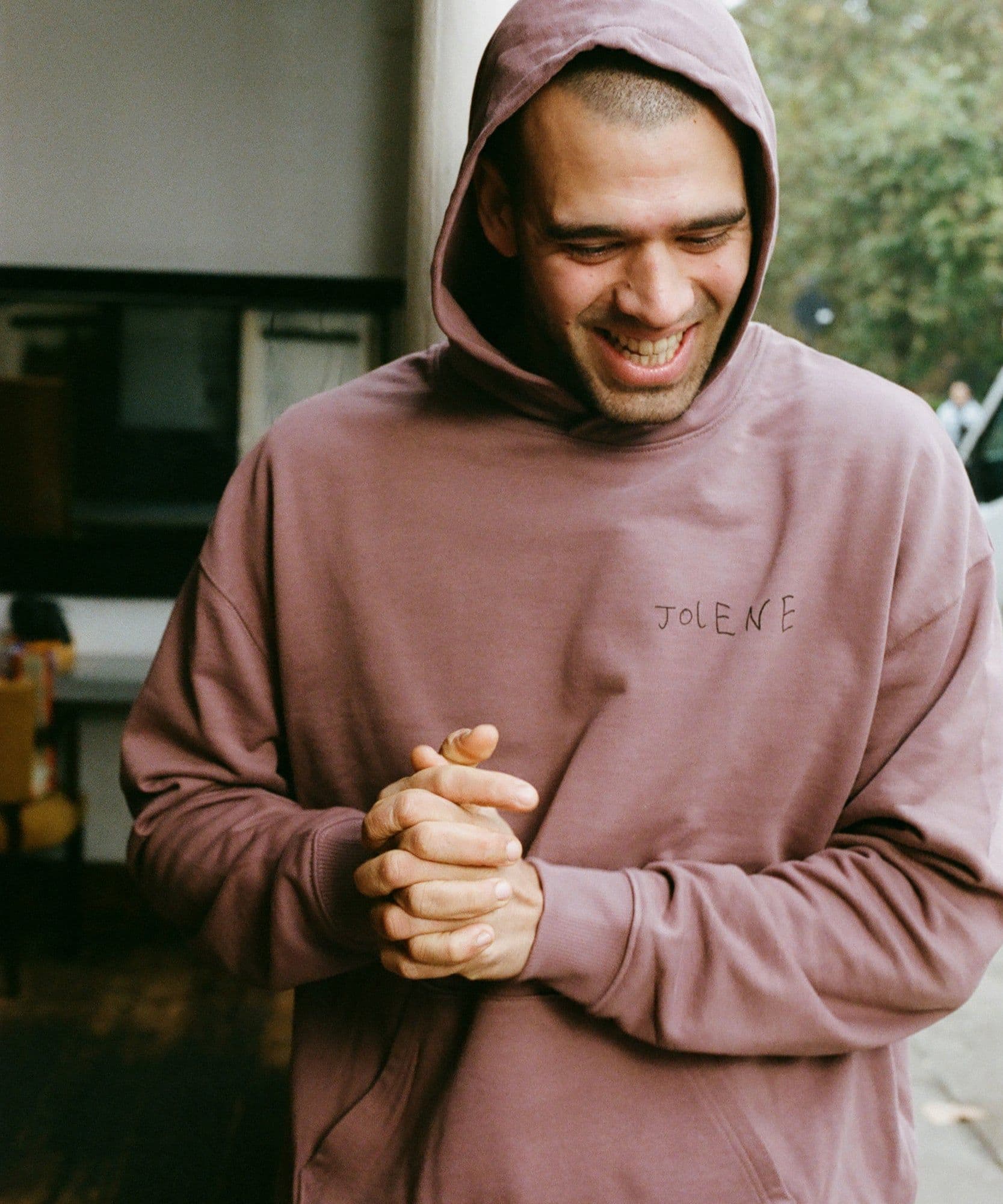 A male model wearing the Jolene bakery J face hoodie in coffee
