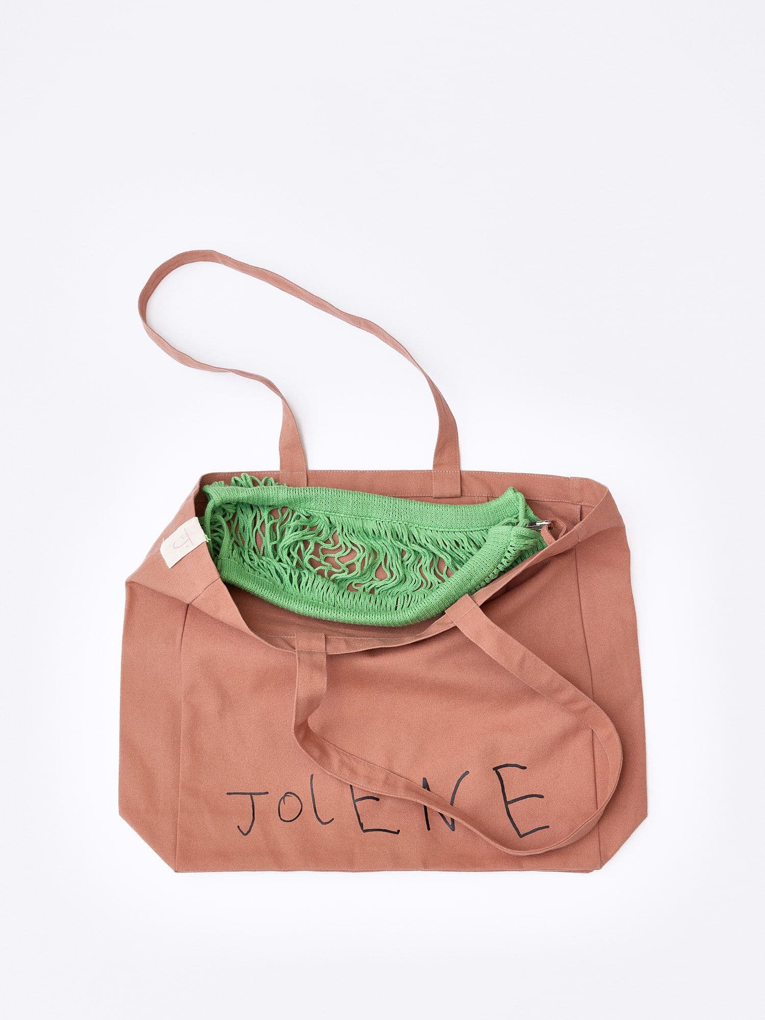 The Jolene bakery pink tote bag with the green net pocket inside it pictured on a white background