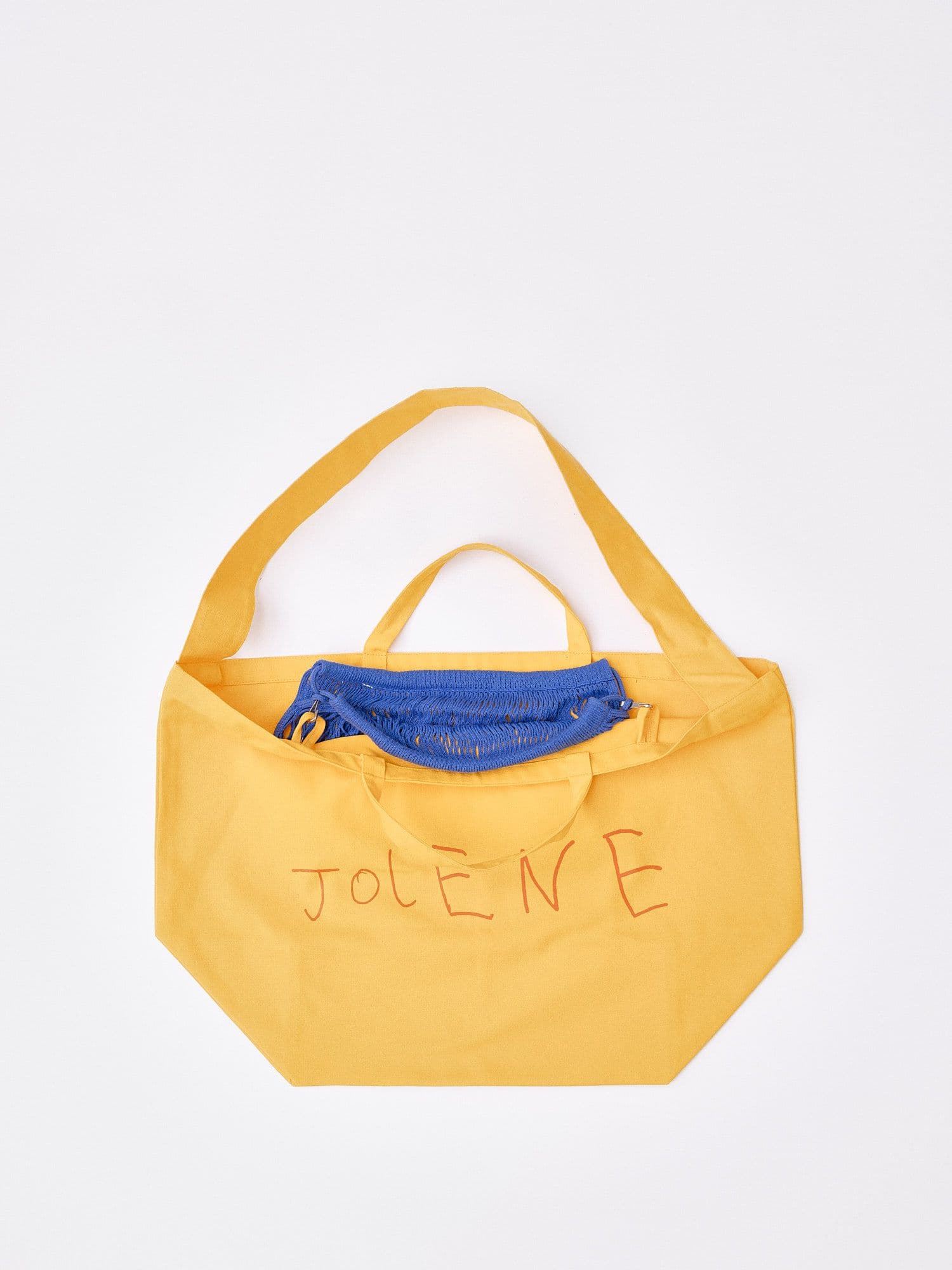 The Jolene bakery yellow tote bag with the blue net pocket inside it pictured on a white background