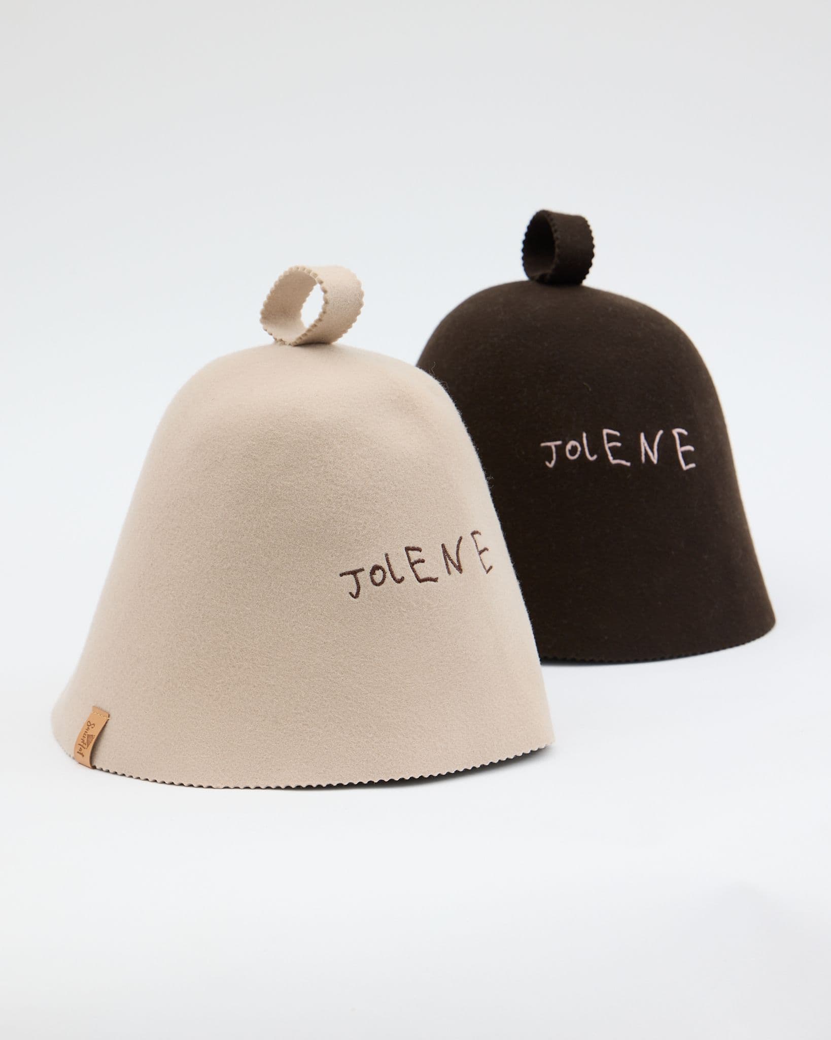 A product shot on a white background of the Jolene Bakery London Sauna Hats. There are two hats side by side show in the two colours brown and stone