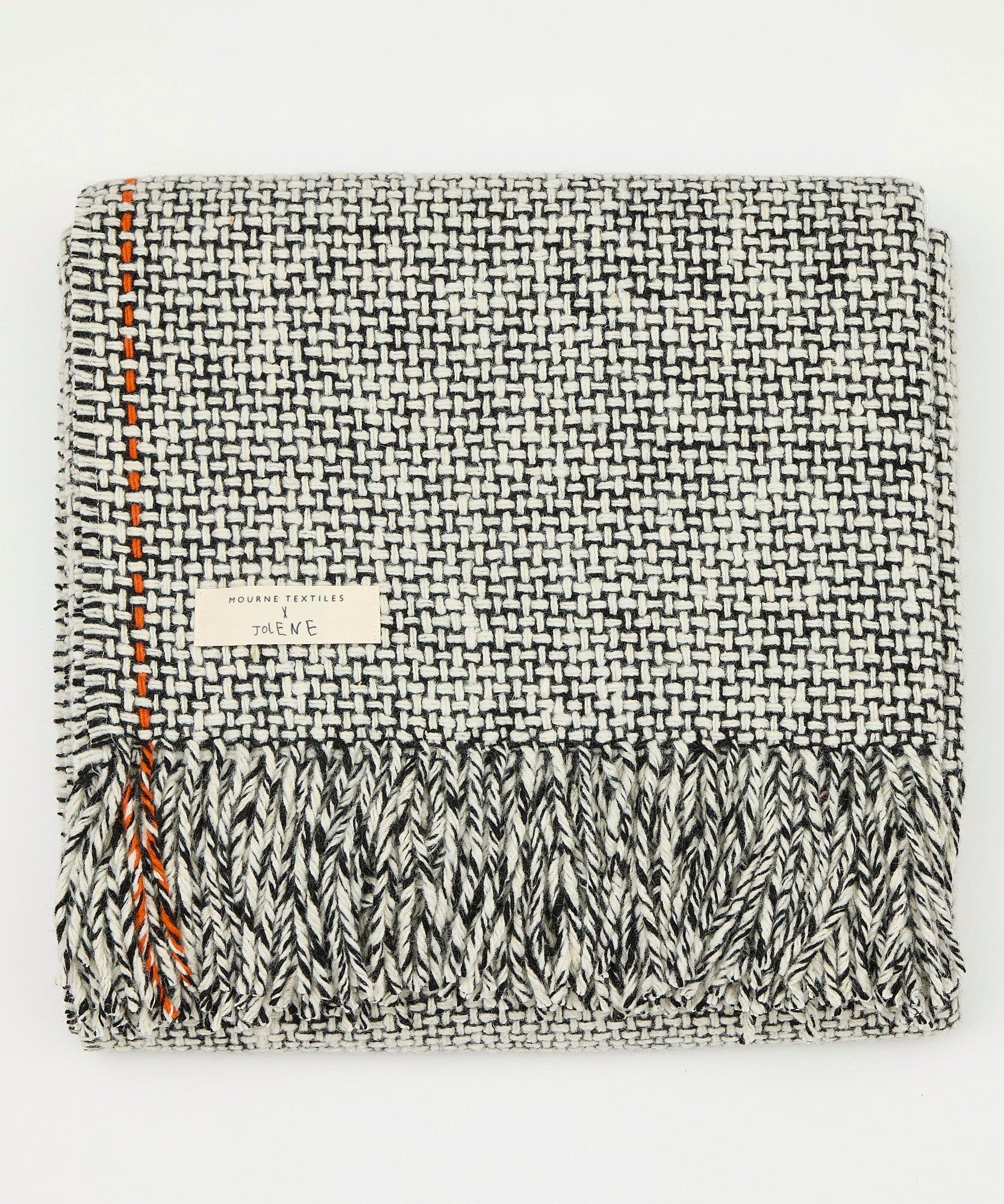 A product image of the Jolene x Mourne Textiles blanket on a white background. It shows the black and white blanket folded up showing the label and details