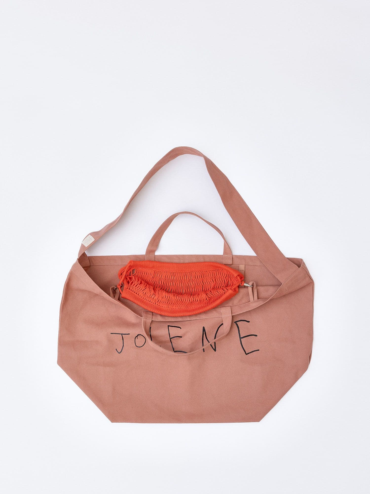 The Jolene bakery pink tote bag with the red net pocket inside it pictured on a white background