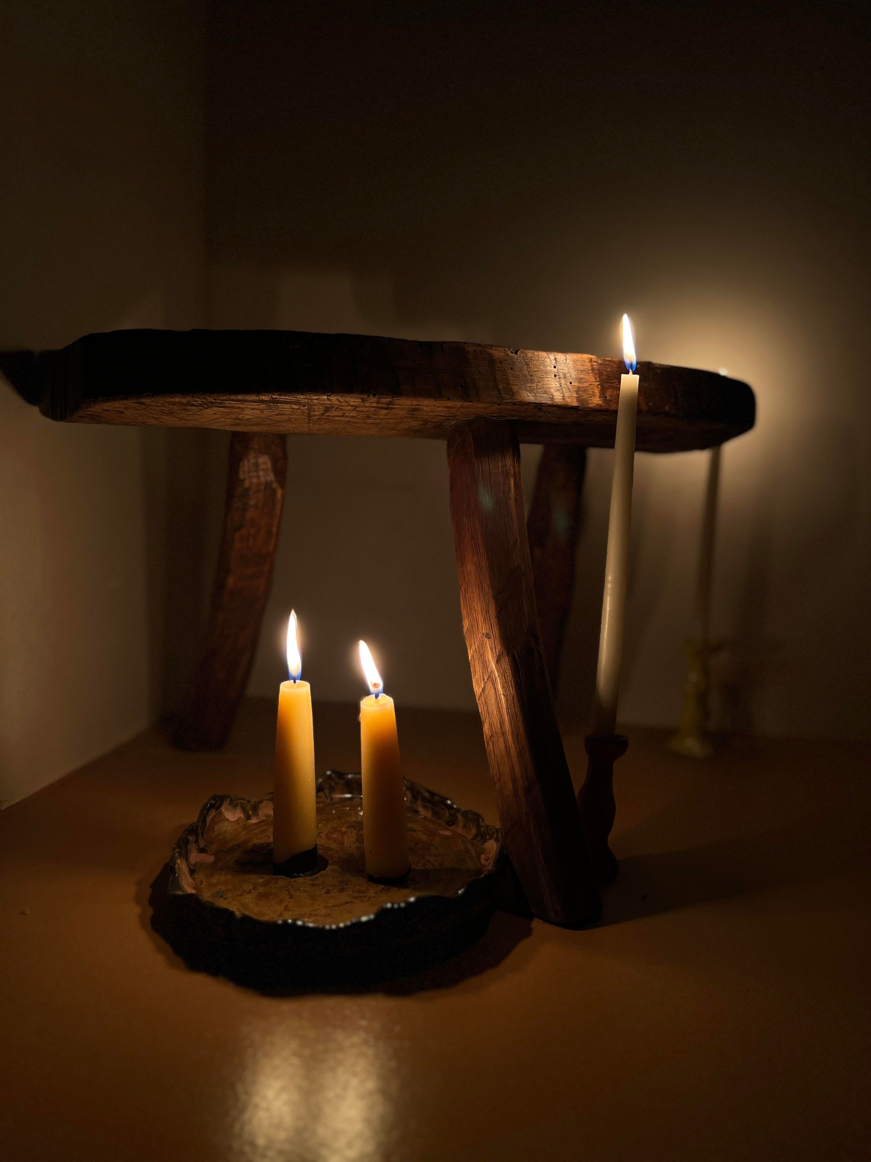 The Jolene bakery x Gina Portman candles lit at night by a wooden stool