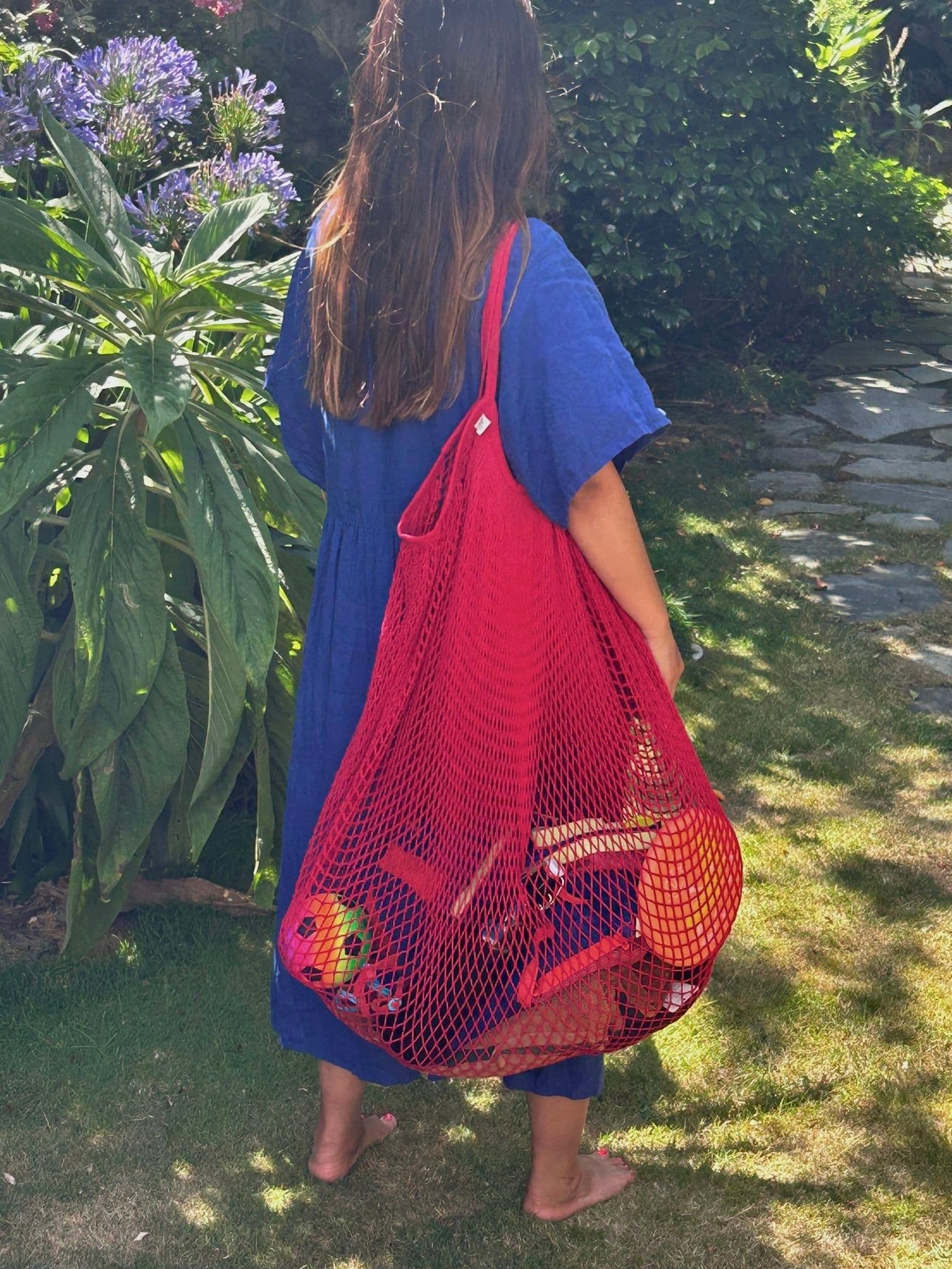 A lady carrying the Jolene Bakery x Filt giant XXL net shopper bag in red